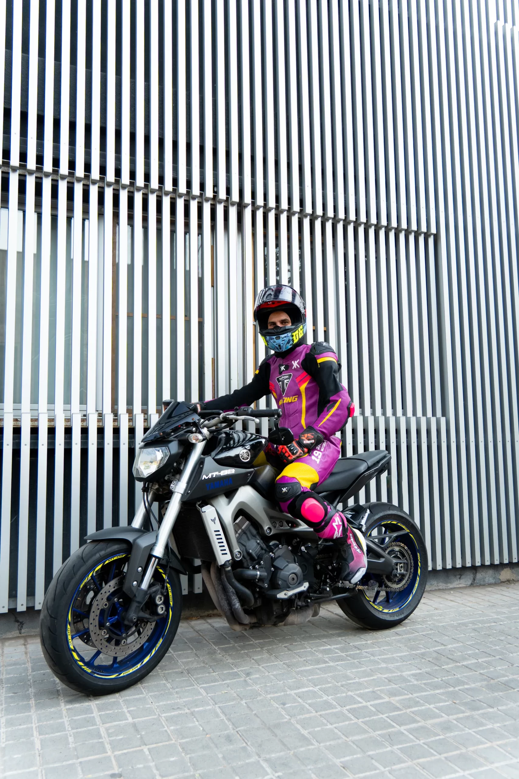 Motorista con mono Doktor personalizado en rosa, negro y amarillo sobre una Yamaha MT-09